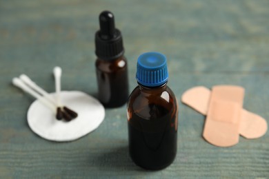 Photo of Bottles of medical iodine on light blue wooden table, closeup