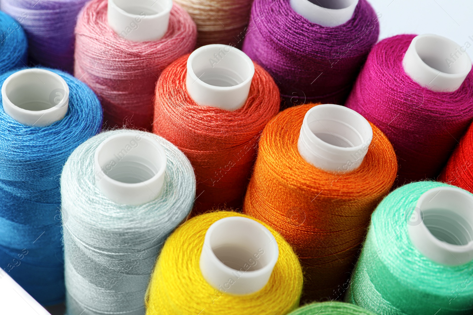 Photo of Set of different colorful sewing threads on white background, closeup