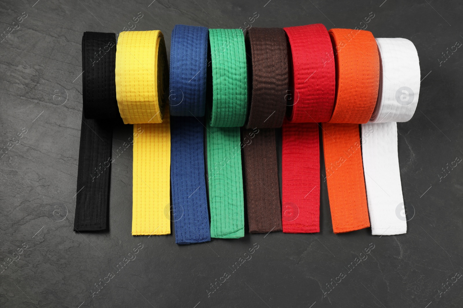 Photo of Colorful karate belts on gray background, flat lay