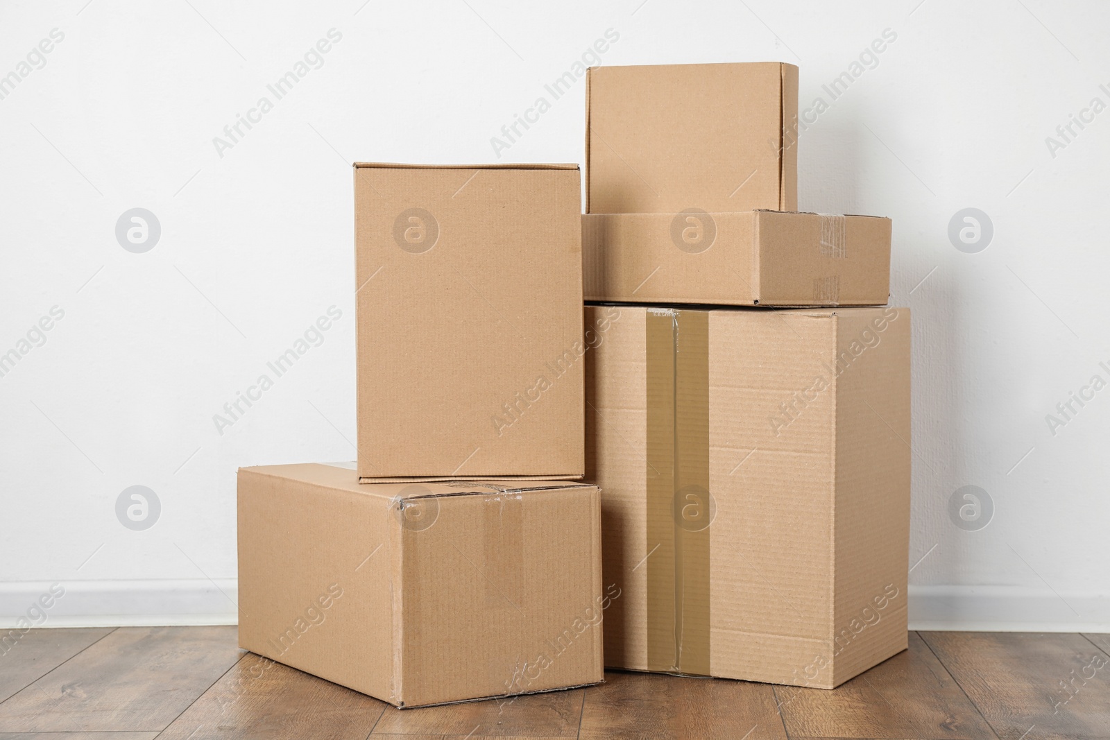 Photo of Pile of cardboard boxes near white wall indoors