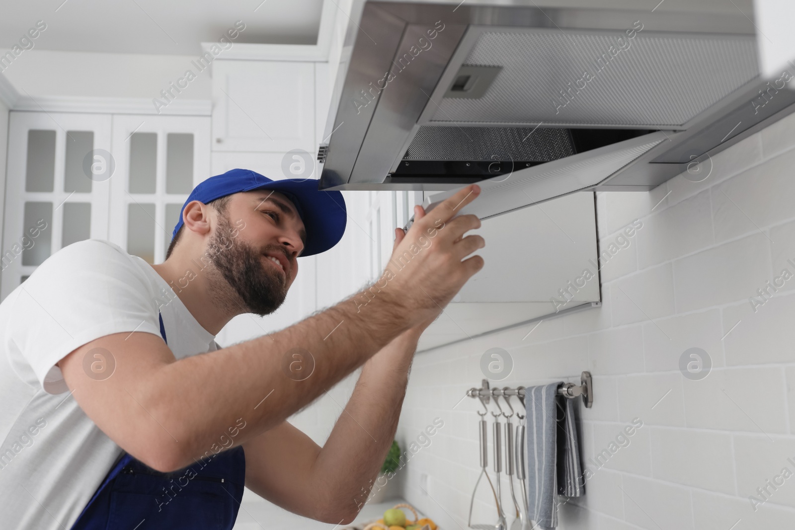 Photo of Worker repairing modern cooker hood in kitchen