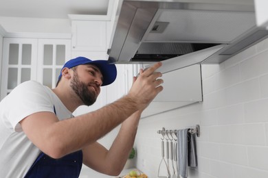 Worker repairing modern cooker hood in kitchen