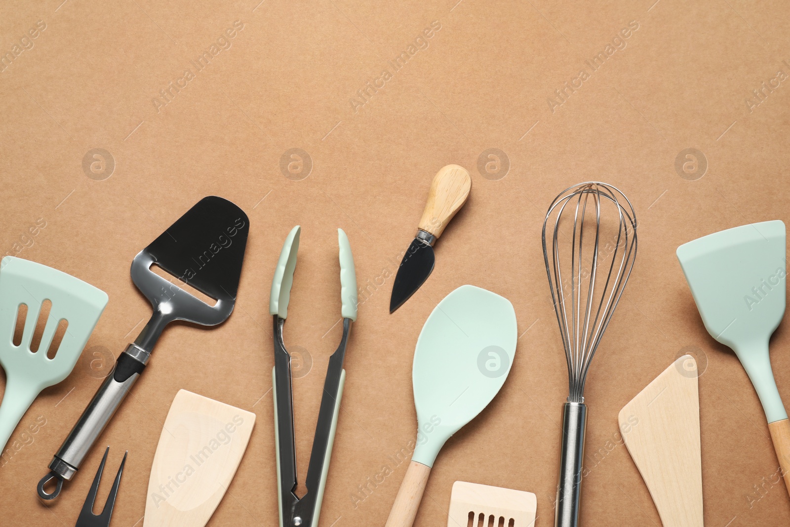 Photo of Different spatulas and other kitchen utensils on brown background, flat lay. Space for text