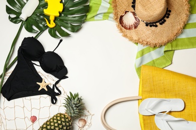 Flat lay composition with swimsuit and beach accessories on white background. Space for text