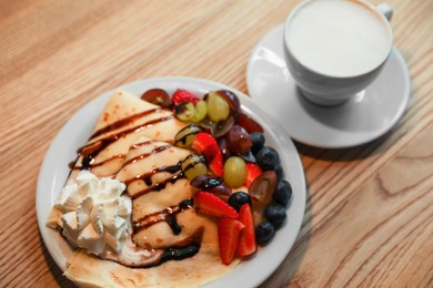 Photo of Cup of aromatic coffee and delicious desserts on wooden table