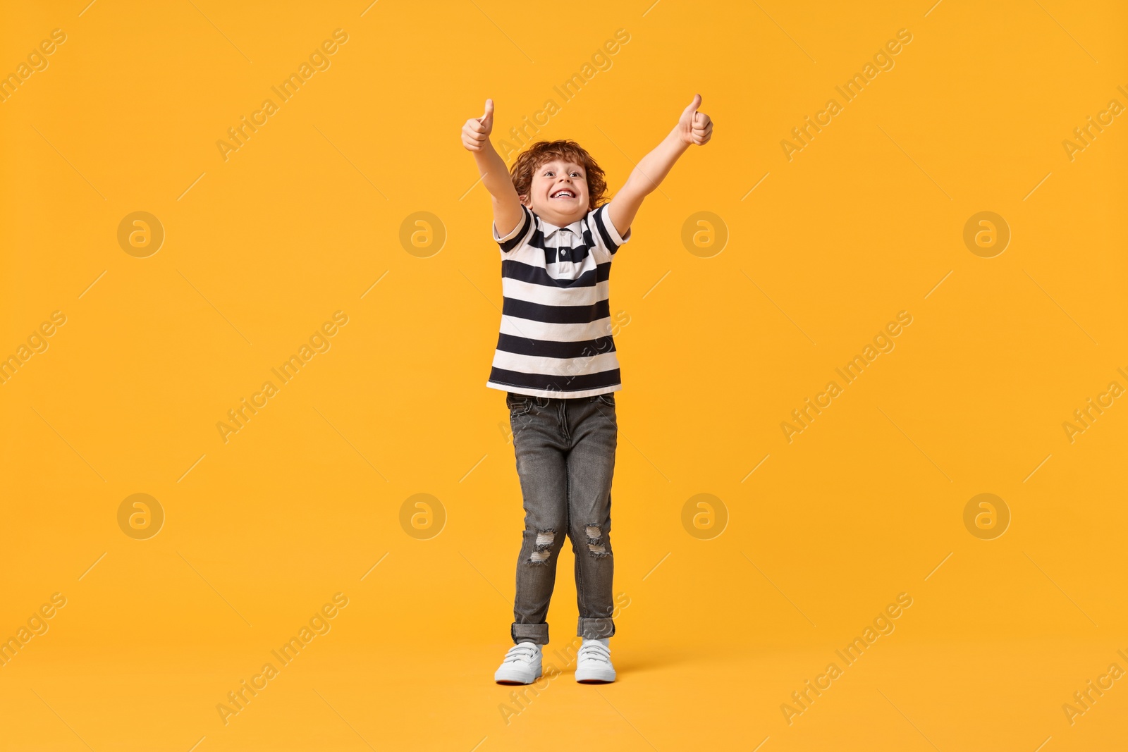 Photo of Happy little boy dancing on yellow background