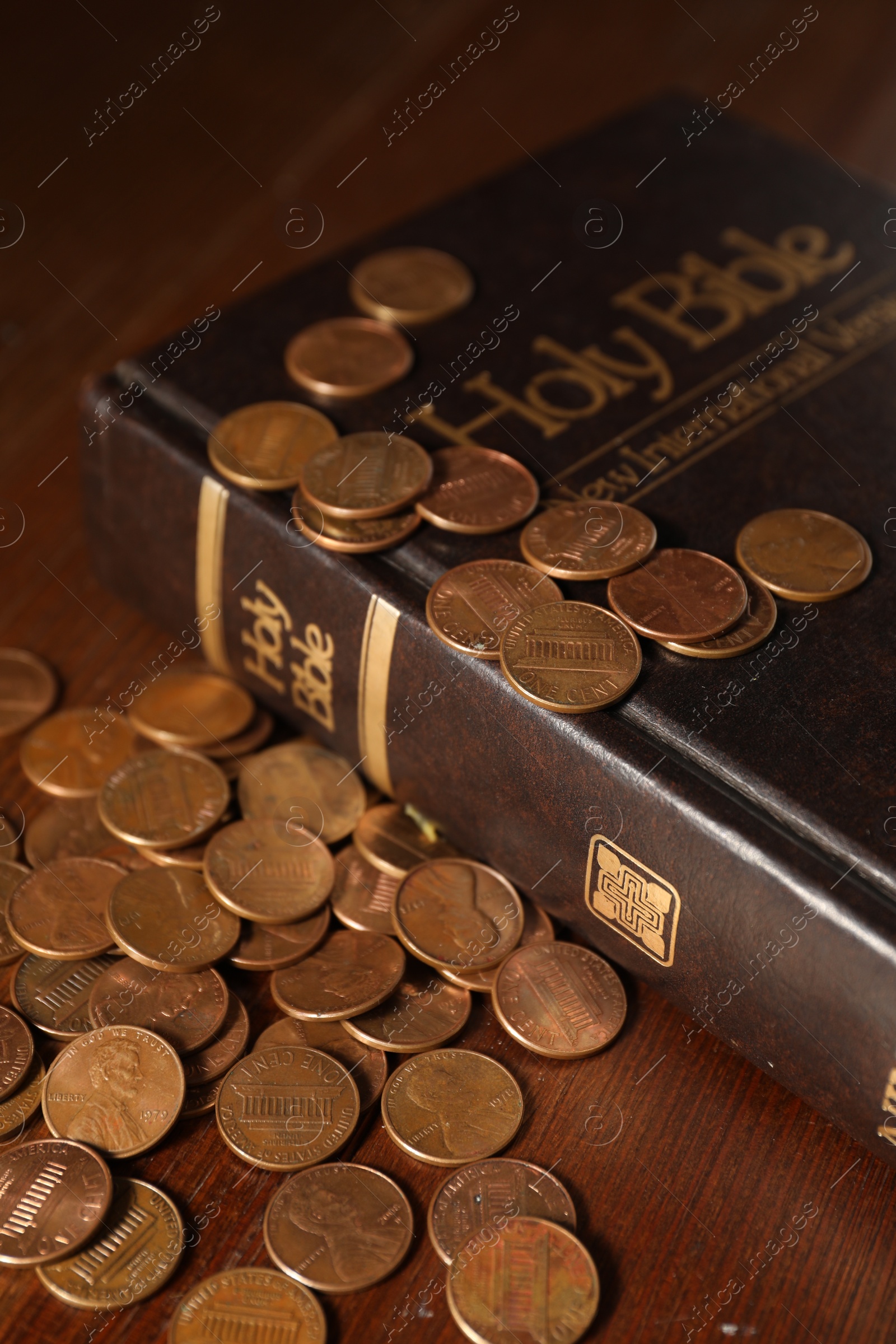 Photo of Donate and give concept. Coins and Bible on wooden table, closeup
