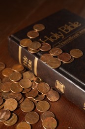 Donate and give concept. Coins and Bible on wooden table, closeup