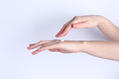 Woman applying cream on her hand against white background, closeup