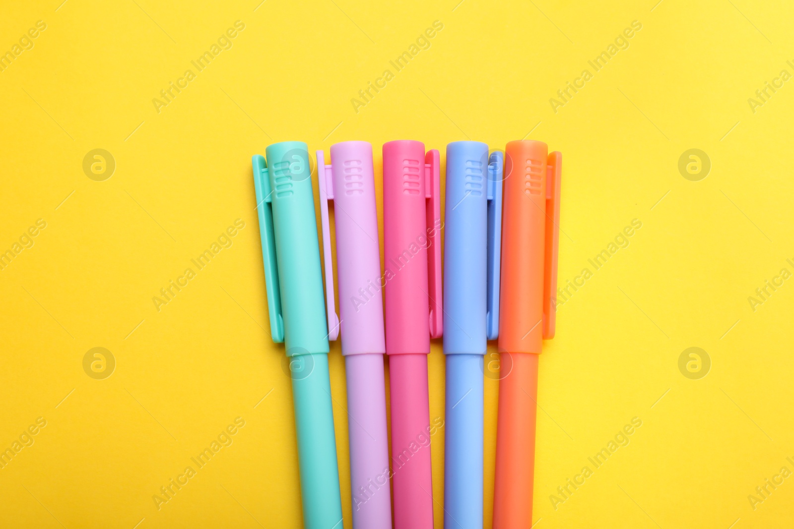 Photo of Many colorful markers on yellow background, flat lay