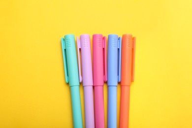 Photo of Many colorful markers on yellow background, flat lay