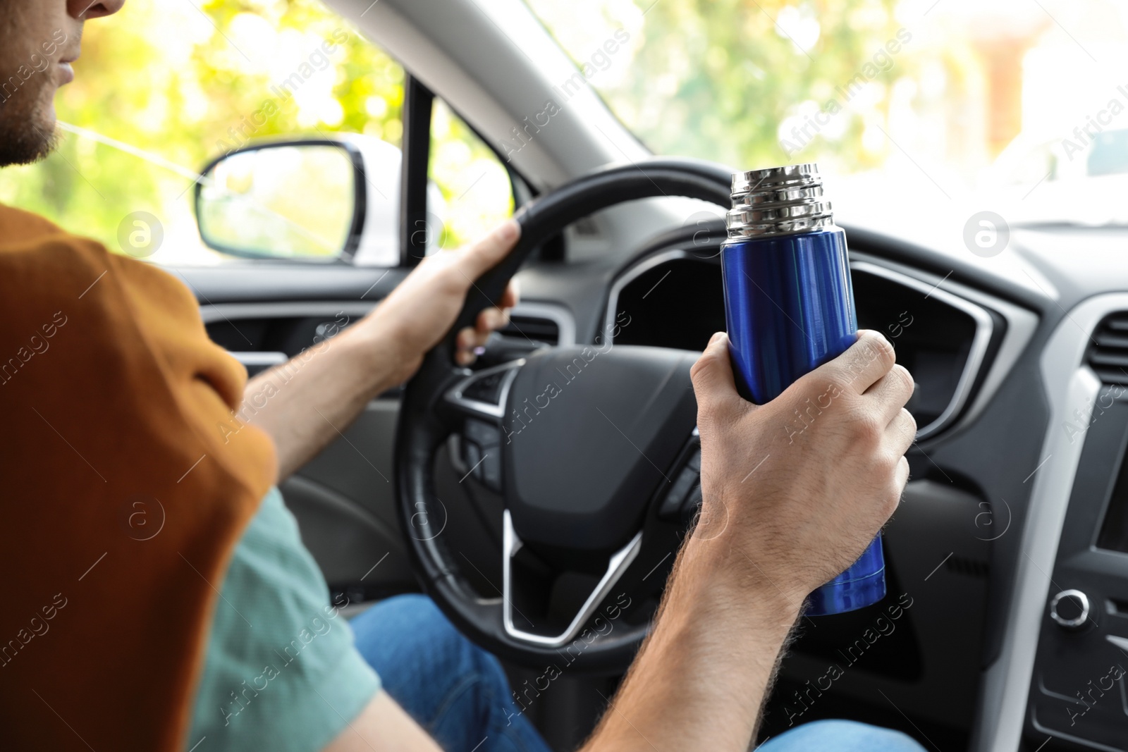 Photo of Man with thermos driving car, closeup view