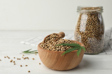 Photo of Organic hemp seeds and leaf in bowl on white table