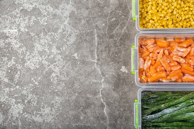 Photo of Plastic containers with different frozen vegetables on table, top view