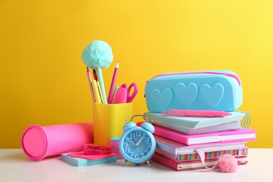 Photo of Different school stationery on white wooden table against yellow background