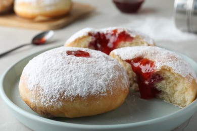 Photo of Delicious donuts with jelly and powdered sugar on plate, closeup