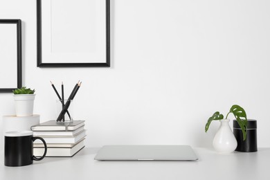 Photo of Home workplace. Laptop, stationery and houseplants on white wooden desk