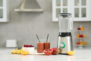 Blender, tasty smoothie and ingredients on white marble table in kitchen