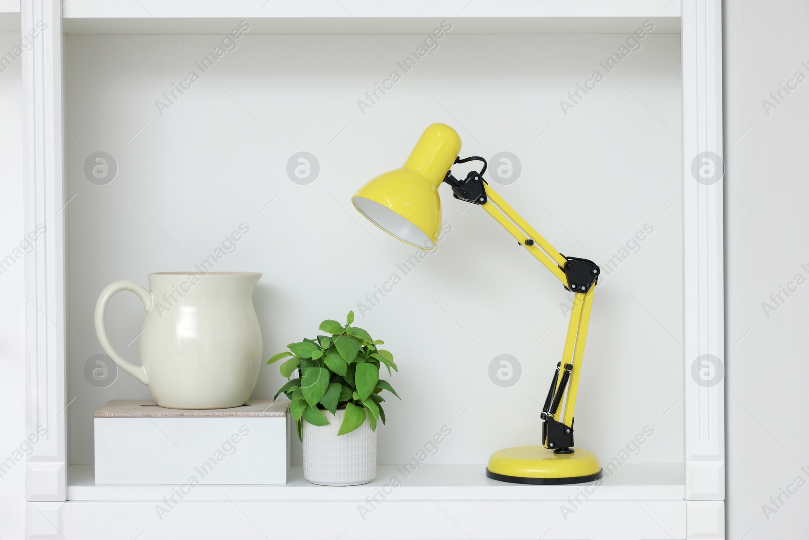 Photo of Shelf with lamp, houseplant and different decor. Interior design