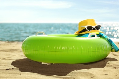 Inflatable ring and beach objects on sand near sea