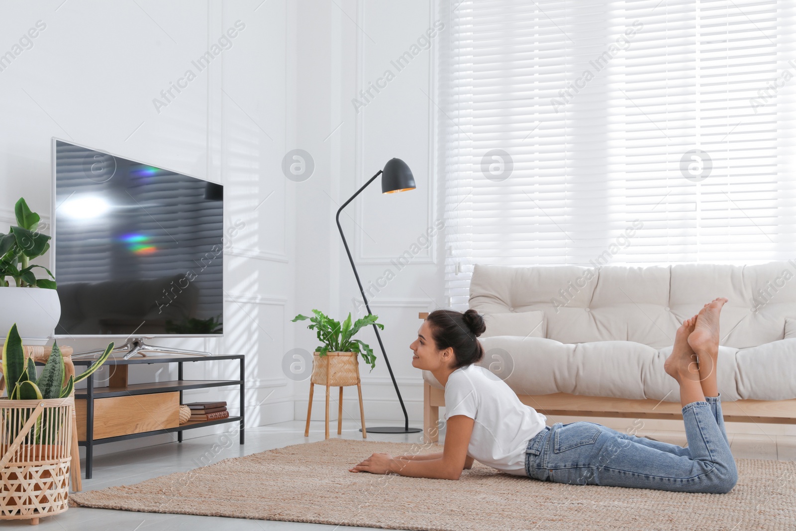 Photo of Woman watching television at home. Living room interior with TV on stand