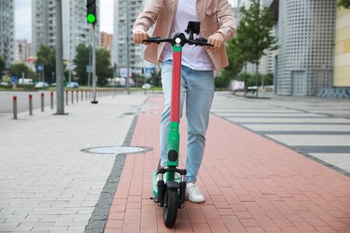 Photo of Man with modern electric kick scooter on city street, closeup
