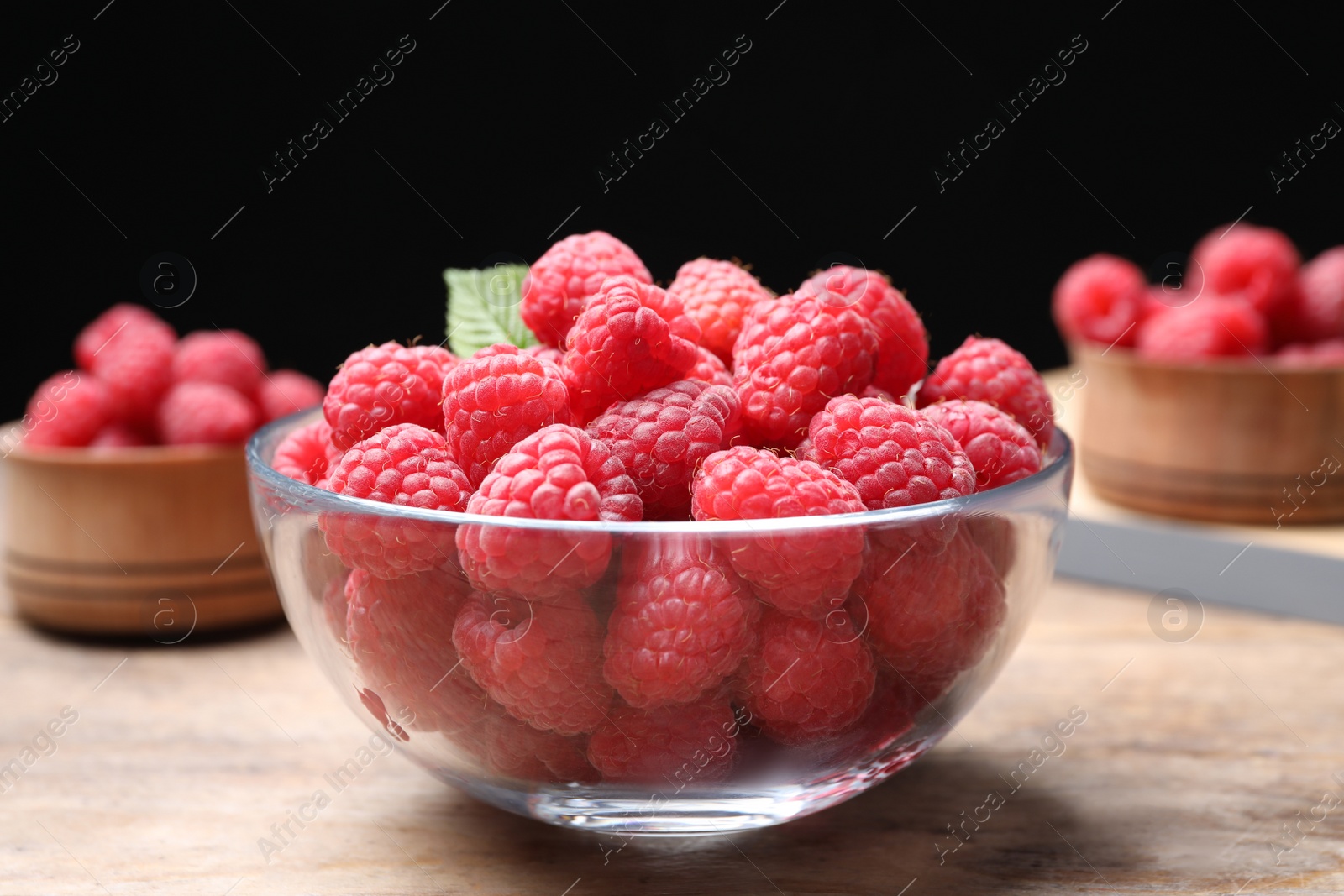 Photo of Delicious fresh ripe raspberries in bowl on wooden table