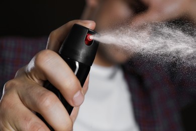 Man covering eyes with hand and using pepper spray, closeup