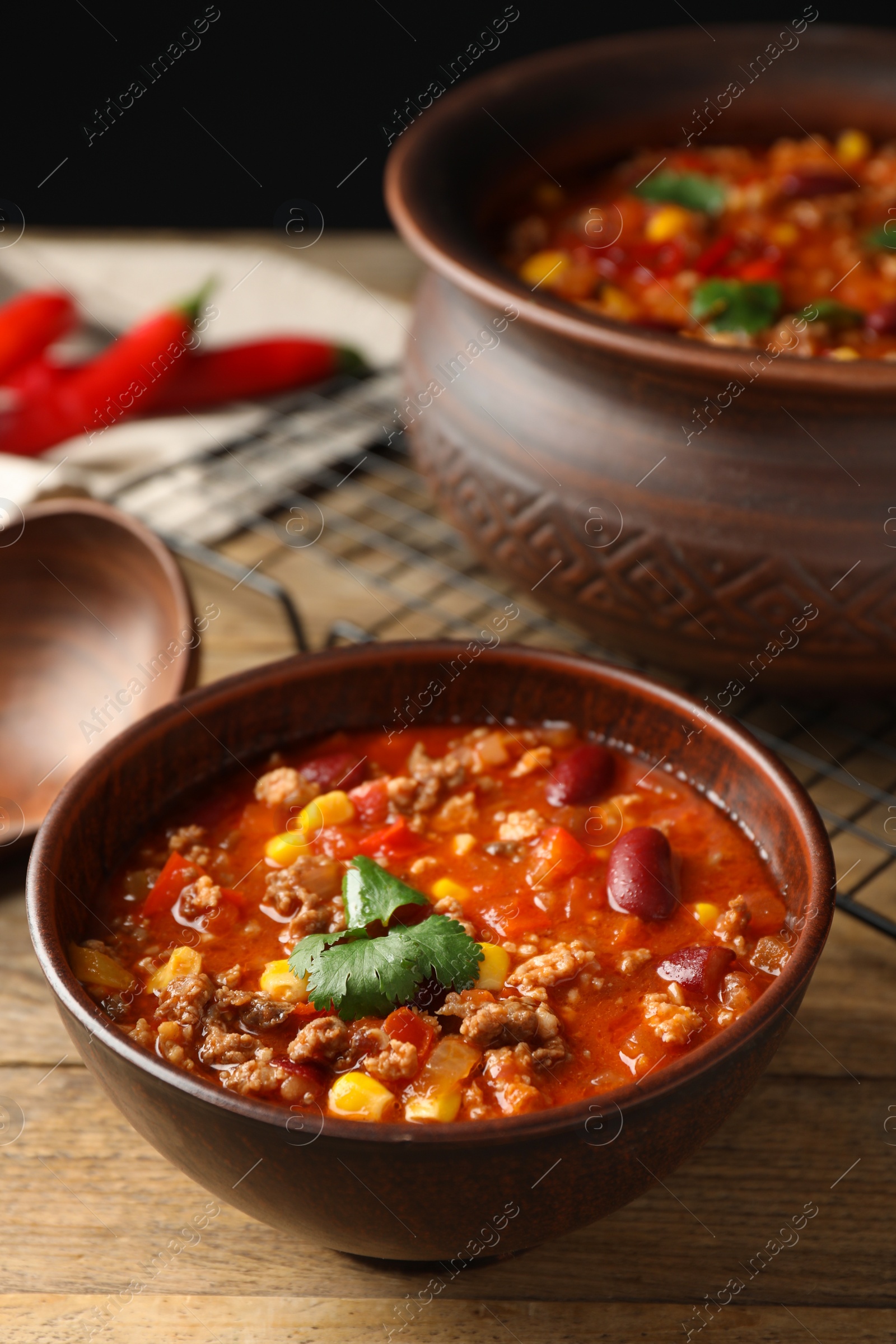 Photo of Bowl with tasty chili con carne on wooden table