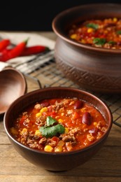 Bowl with tasty chili con carne on wooden table