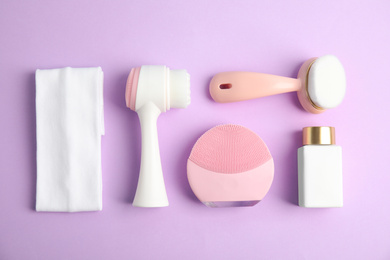 Photo of Flat lay composition with face cleansing brushes on violet background. Cosmetic tools