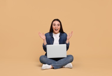 Photo of Happy young woman with laptop on beige background