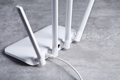 Photo of New white Wi-Fi router on grey textured table, closeup