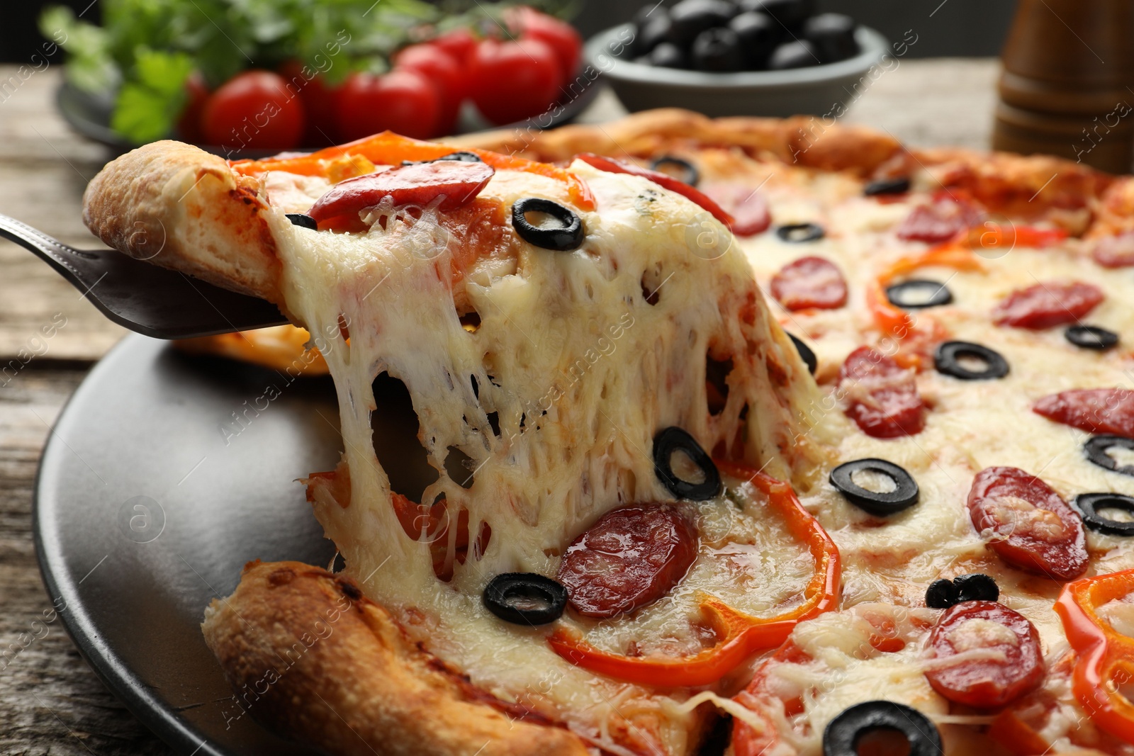 Photo of Taking piece of tasty pizza at table, closeup