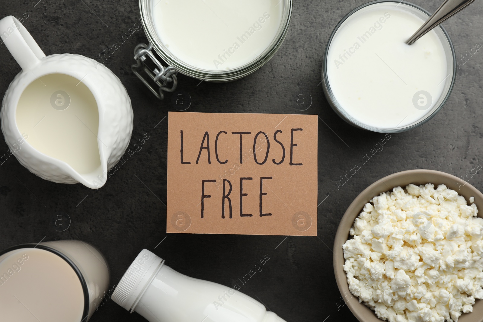 Photo of Many different dairy products and card with phrase Lactose free on grey textured table, flat lay