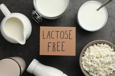 Photo of Many different dairy products and card with phrase Lactose free on grey textured table, flat lay