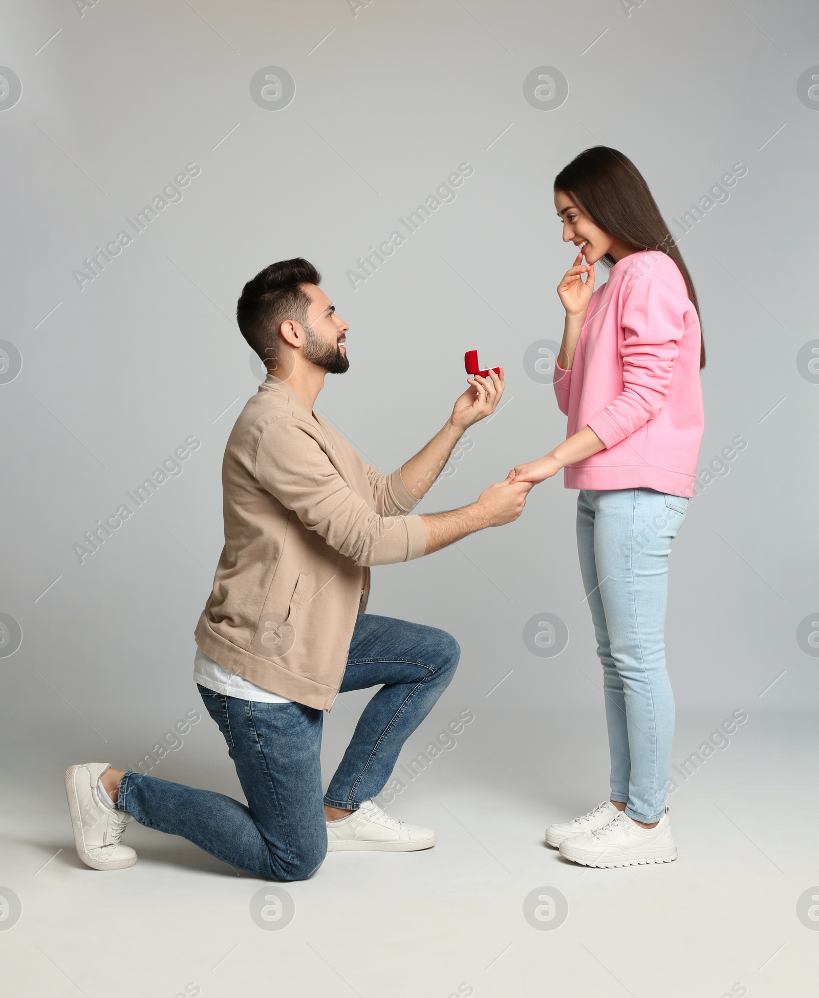 Photo of Man with engagement ring making marriage proposal to girlfriend on light grey background