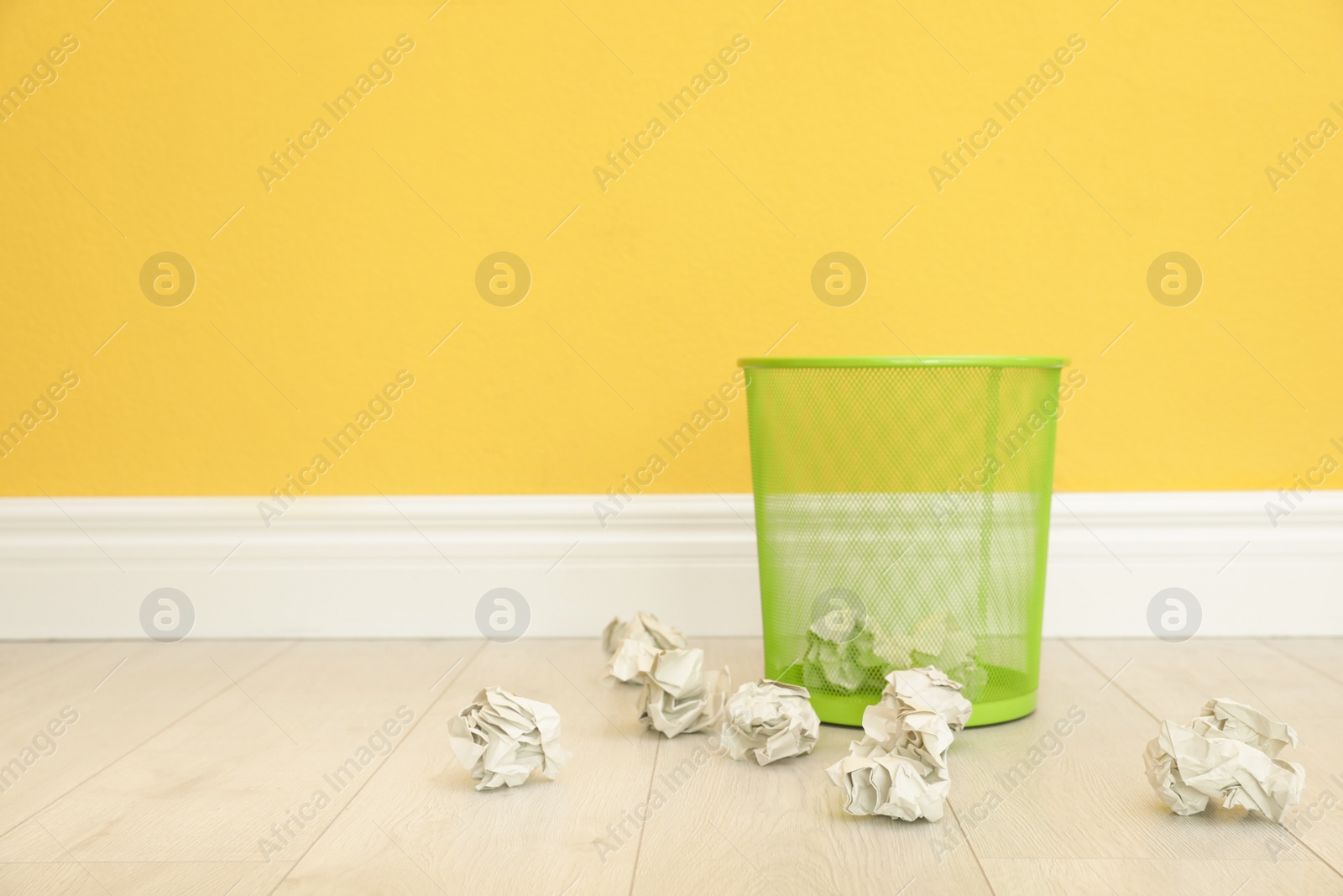 Photo of Metal bin and crumpled paper against color wall, space for text