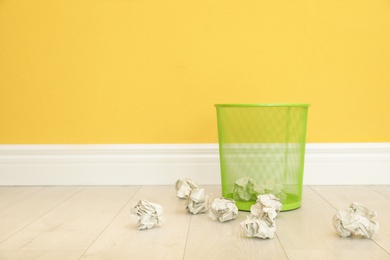 Photo of Metal bin and crumpled paper against color wall, space for text