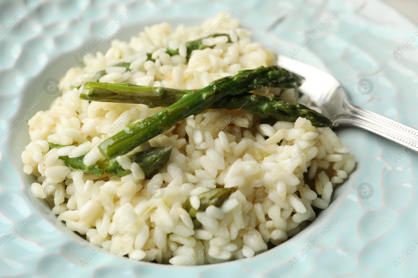 Photo of Delicious risotto with asparagus in plate, closeup