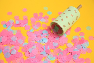Photo of Party popper with bright confetti on orange background