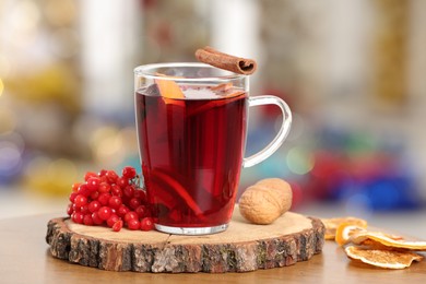 Aromatic mulled wine in glass cup on wooden table against blurred background