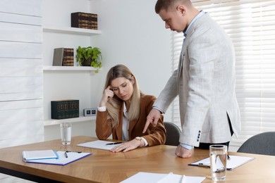 Businessman pointing on wrist watch while scolding employee for being late in office