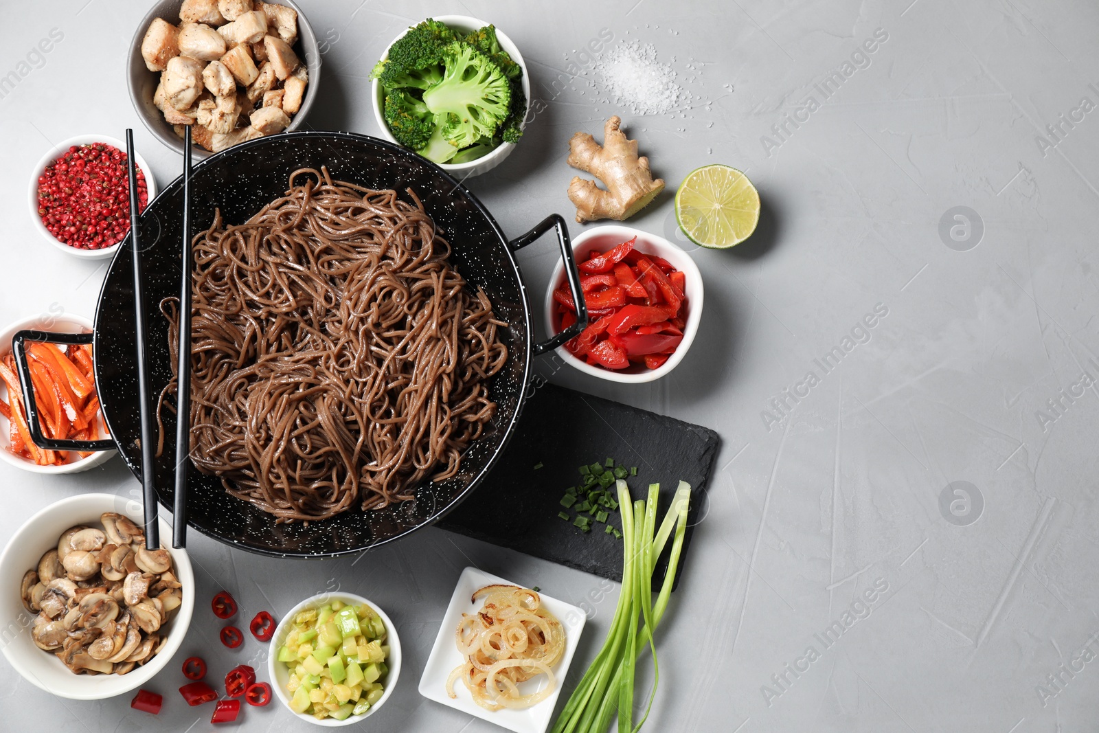 Photo of Wok with noodles, chicken and other products on light grey table, flat lay. Space for text