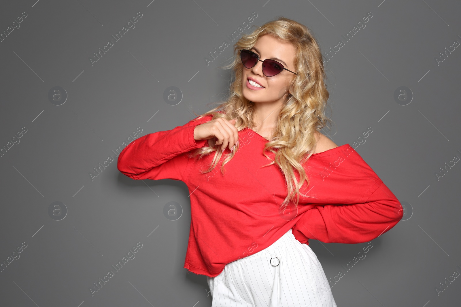 Photo of Stylish young woman with sunglasses posing on grey background