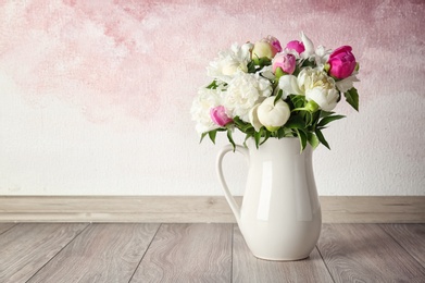 Vase with bouquet of beautiful flowers on floor