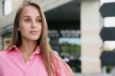 Photo of Beautiful young woman in stylish shirt on city street, space for text