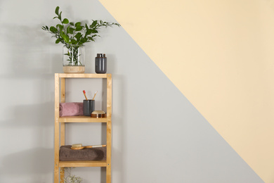 Shelving unit with toiletries near light wall indoors, space for text. Bathroom interior element