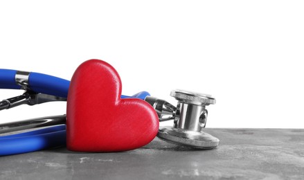 Photo of Stethoscope and red heart on grey table against white background