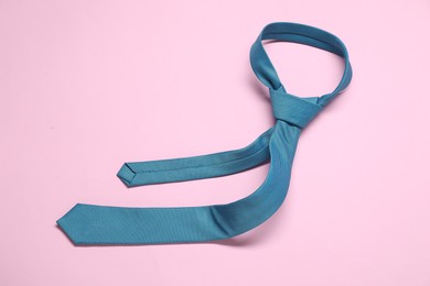 Photo of Blue necktie on pink background, above view